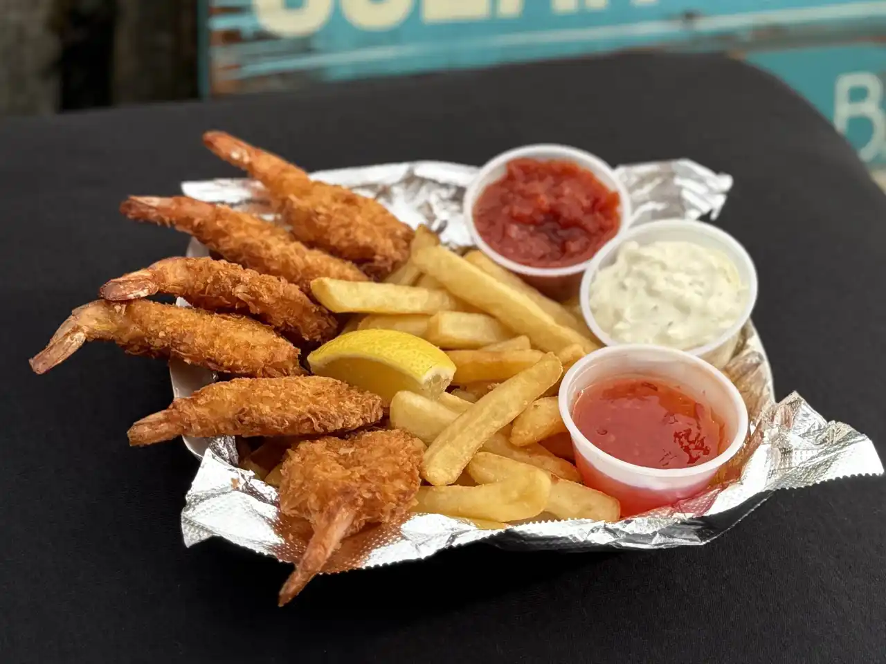 Fried coconut shrimp boat with fries and sauce cups
